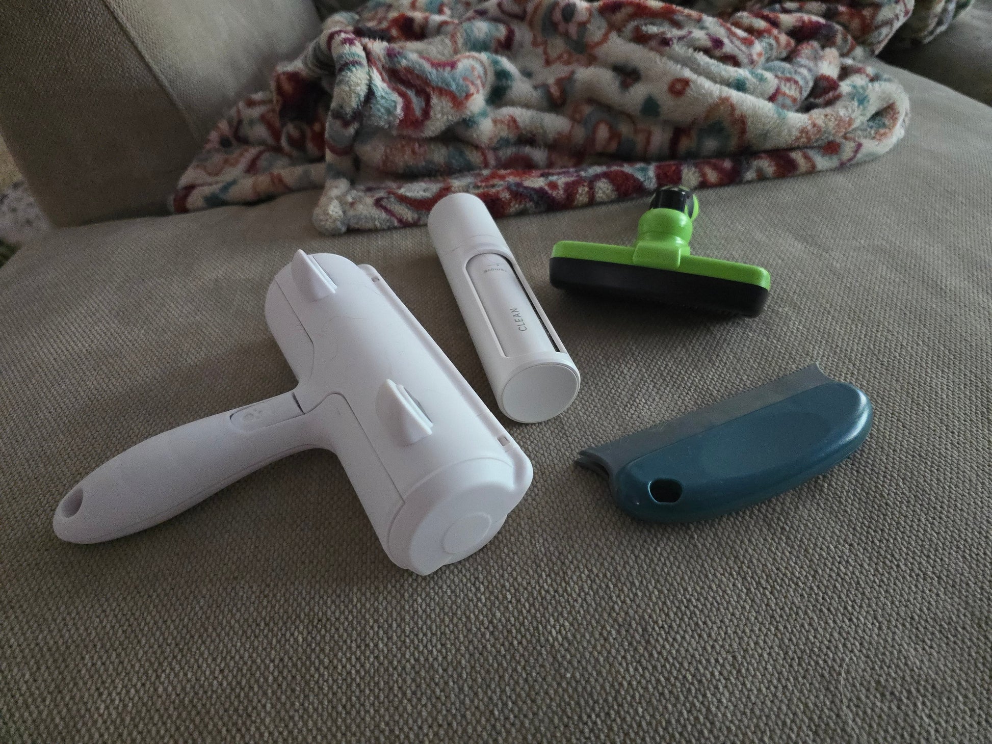 TidyTuft Mini Roller on a couch cushion alongside the full-size roller and grooming tools