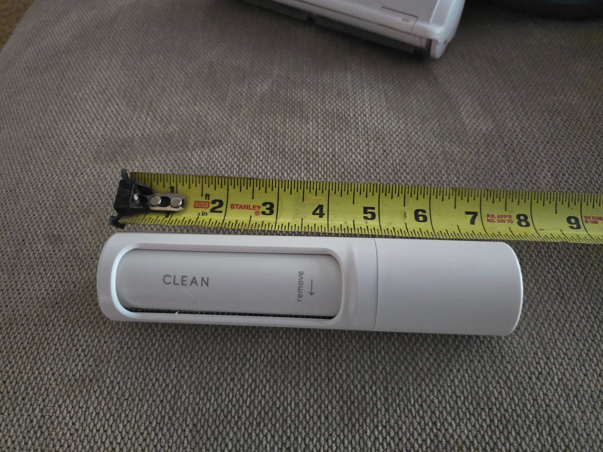 TidyTuft Mini Roller next to a tape measure showing its 8 inch slim body and CLEAN chamber window