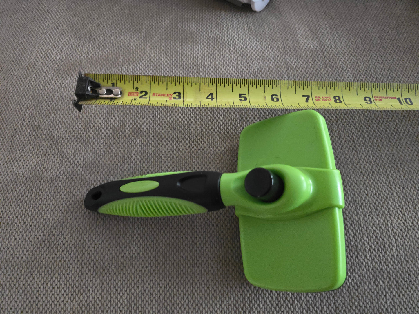 TidyTuft Self-Cleaning Slicker Brush shown full length beside a tape measure, about 8 inches